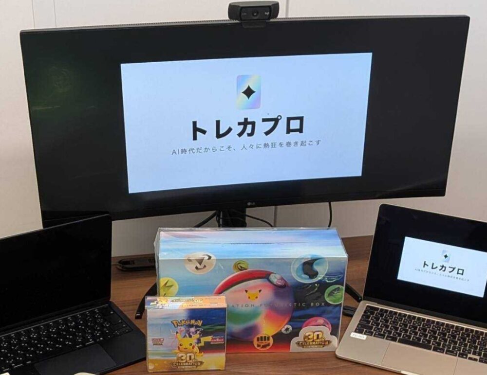 トレカプロのオフィス。モニターにトレカプロのロゴ、机にポケモンカード30周年の記念ボックス