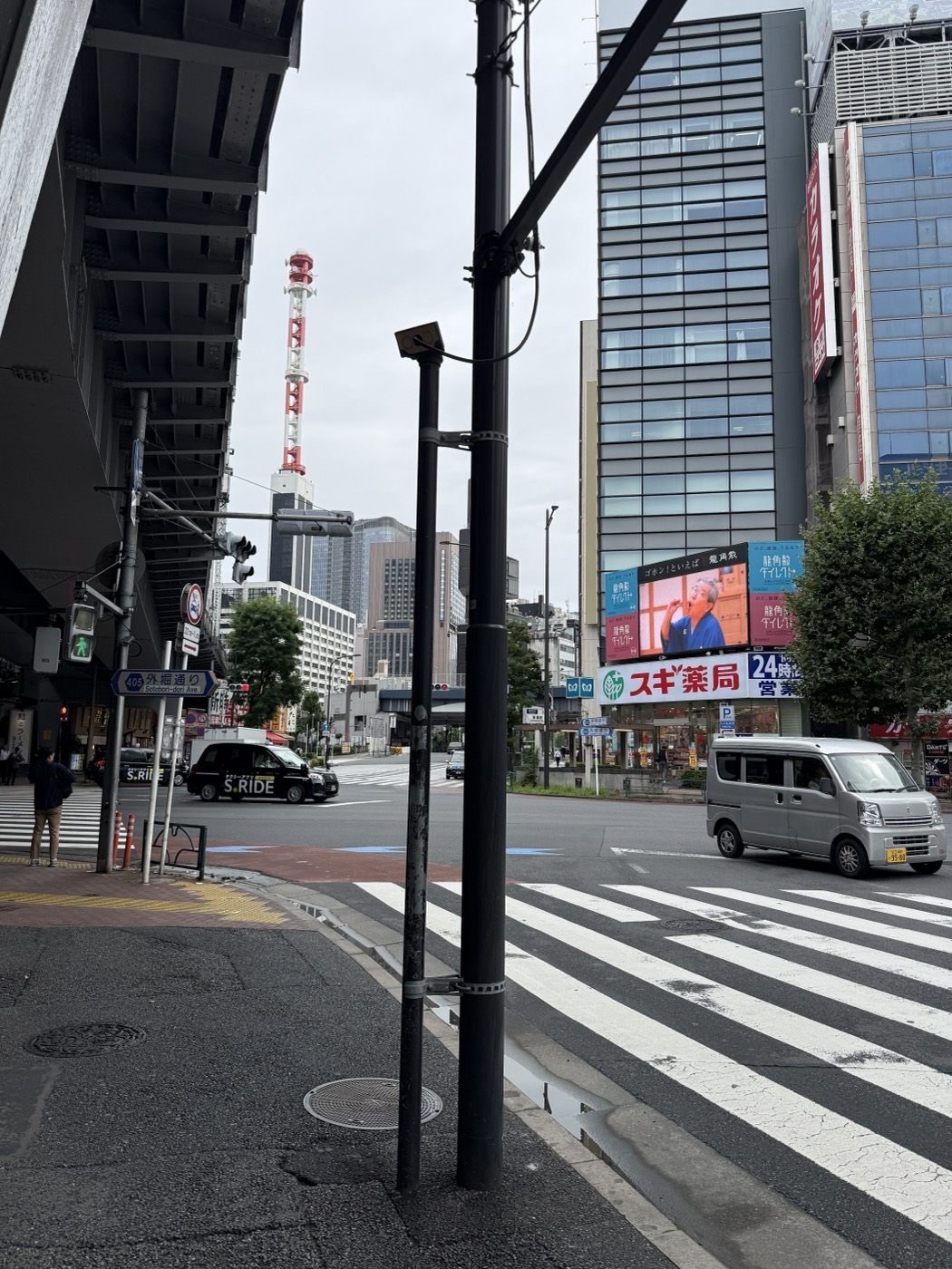 外堀通りの交差点越しにスギ薬局のビル（新橋プレイス）